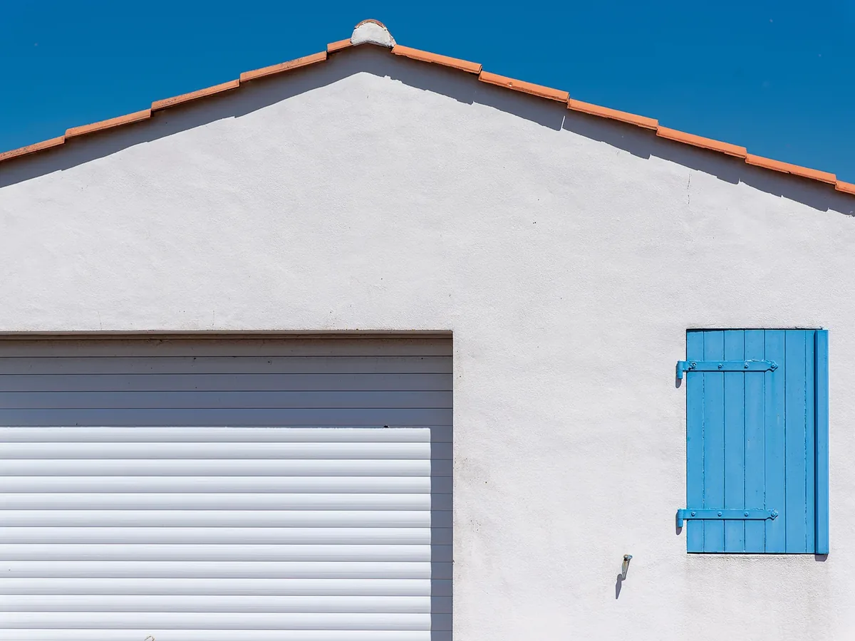 White stucco wall with blue-painted shutters