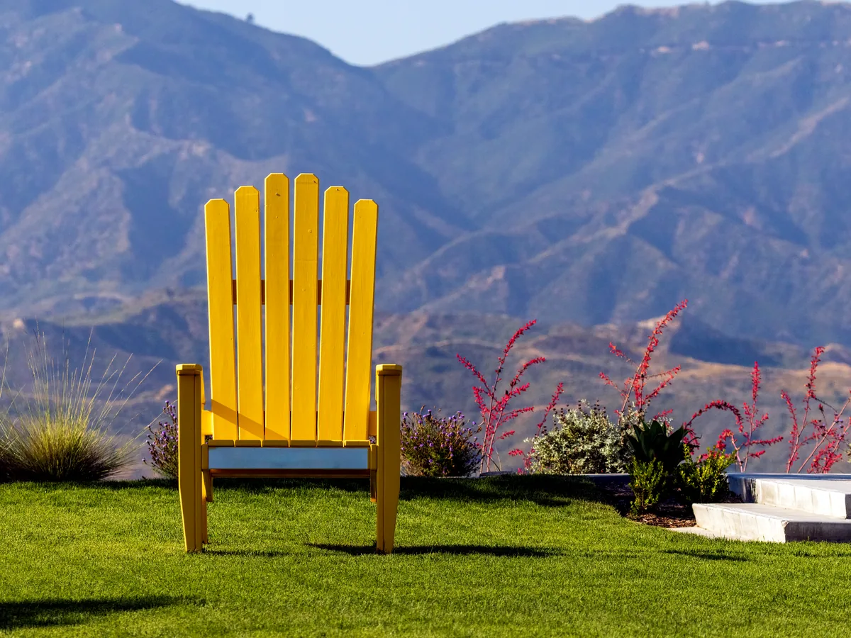 Yellow chair on artificial turf with a hillside view